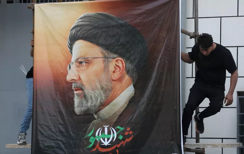 Men place a huge portrait of late Iranian president Ebrahim Raisi at the gate of the Islamic republic's embassy in Baghdad during a condolences service on May 20, 2024 for the president and his entourage who were killed in a helicopter crash in Iran the previous day. (Photo by AHMAD AL-RUBAYE / AFP)