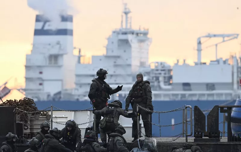 German special police force members arrive as the Floating Storage Regasification Unit (FSRU) ship "Hoegh Esperanza" docks at the Liquefied Natural Gas (LNG) terminal at the port of Wilhelmshaven, northern Germany, December 15, 2022. - Germany is set to receive its first floating gas terminal, as the country looks to replace Russian supplies it previously received via pipeline. The "Hoegh Esperanza" will dock at the northern port of Wilhelmshaven and is loaded with an initial shipment of liquefied natural gas (LNG). The platform that will connect the unit to the onshore gas network was built at breakneck speed in a matter of months and will be inaugurated by Chancellor Olaf Scholz on December 17. (Photo by FABIAN BIMMER / POOL / AFP)