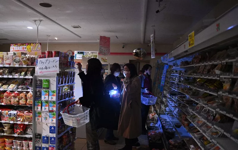 People shop in a store in a residential area during a power outage in Koto district in Tokyo on March 16, 2022, after a powerful 7.3-magnitude quake jolted east Japan. (Photo by Philip FONG / AFP)