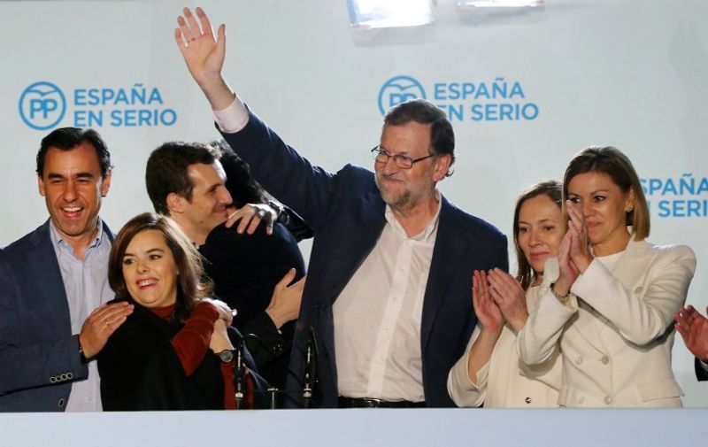 Spanish Prime Minister and Popular Party (PP) leader and candidate for the upcoming December 20 general election, Mariano Rajoy (3rd R) waves after delivering a speech next to his wife Elvira Fernandez (R), Vice President of the Spanish government Soraya Saenz de Santamaria (2nd L), PP Secretary General and candidate Maria Dolores de Cospedal (R) and other party members at PP's headquarters after the results of Spain's general election in Madrid on December 20, 2015. Spain's ruling conservative Popular Party won the most seats in parliament in a general election today but lost its absolute majority, partial results showed with over 80 percent of votes counted.    AFP PHOTO/ CESAR MANSO / AFP / CESAR MANSO