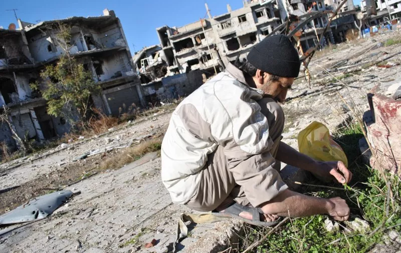 A Syrian man looks for herbs to eat with his family in the heavily damaged neighbourhood of Juret al-Shiyah, which is allegedly exposed to the fire of government forces' snipers, in the central Syrian city of Homs on February 1, 2014. At UN-brokered peace talks between the Syrian government and the opposition in Geneva last week, the only tangible pledge to emerge concerned aid for civilians in rebel-held parts of the central city of Homs, besieged by the military since June 2012.  AFP PHOTO / BASSEL TAWIL / AFP / BASSEL TAWIL / BASSEL TAWIL