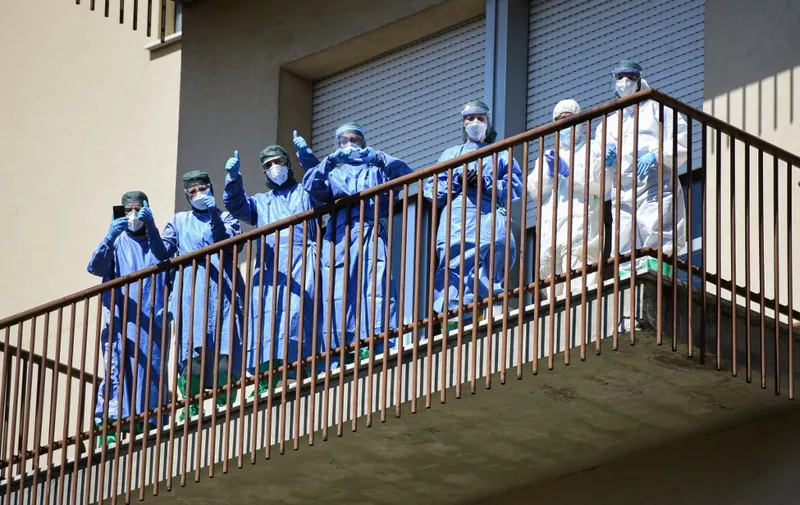 Health workers wearing protective gear take part in a flash mob at the Pavullo hospital near Modena, on April 9, 2020 during the country's lockdown aimed at curbing the spread of the COVID-19 infection, caused by the novel coronavirus. - The flash mob, organized by the Regional Civil Protection Agency aimed at, with its officials, employees and volunteers, thanking all those who are engaged daily to manage and overcome the emergency related to the coronavirus pandemic. (Photo by Piero CRUCIATTI / AFP)