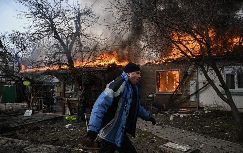 A man runs in front of a house burning after being shelled in the city of Irpin, outside Kyiv, on March 4, 2022. - More than 1.2 million people have fled Ukraine into neighbouring countries since Russia launched its full-scale invasion on February 24, United Nations figures showed on March 4, 2022. (Photo by Aris Messinis / AFP)