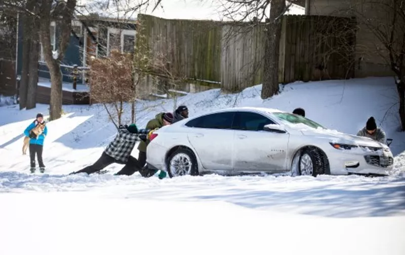 AUSTIN, TX - FEBRUARY 15: East Austin residents push a car out of the snow on February 15, 2021 in Austin, Texas. Winter storm Uri has brought historic cold weather to Texas, causing traffic delays and power outages, and storms have swept across 26 states with a mix of freezing temperatures and precipitation.   Montinique Monroe/Getty Images/AFP (Photo by Montinique Monroe / GETTY IMAGES NORTH AMERICA / AFP)
