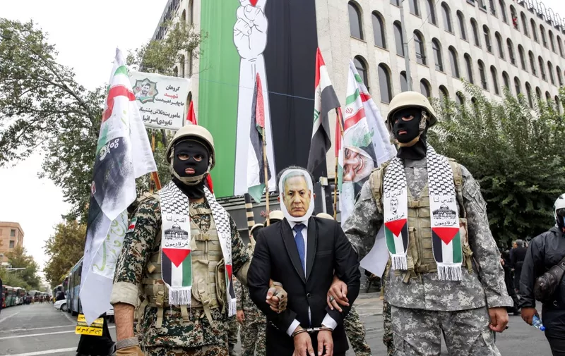 Members of the Iranian Basij forces stage a mock arrest of a man dressed like Israeli Prime Minister Benjamin Netanyahu during an anti-Israeli rally to show their solidarity with Palestinians in the capital Tehran on October 13, 2023. Thousands of Iranians took to the streets of Tehran on Friday in a show of support for Palestinians amid a bloody conflict between Israel and Hamas. (Photo by AFP)