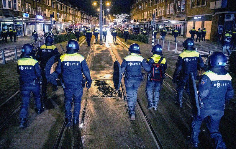 Dutch police officers patrol in the streets of Rotterdam, during the curfew time, on January 26, 2021, a day after police clashed with groups of demonstrators protesting against the introduction of new measures, including the curfew, to fight against the spread of the Covid-19. - In South Rotterdam and in the city center, several people were arrested for, among other things, gathering and not being able to show proof of identity. The police are massively present in the city after the riots of the day before and check people walking in groups on the street. (Photo by STR / ANP / AFP) / Netherlands OUT