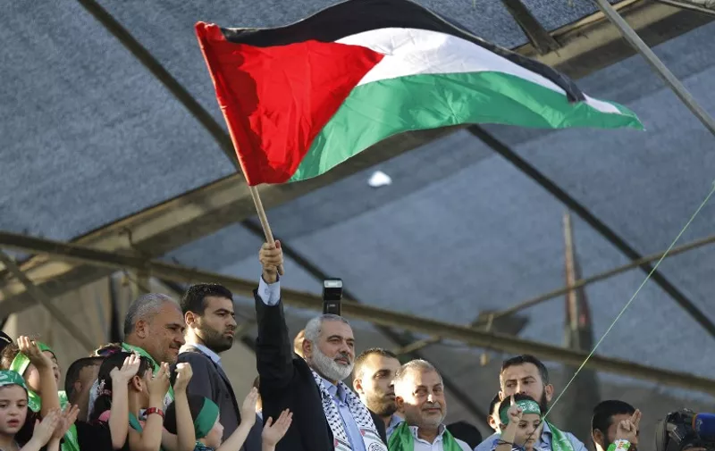 Hamas top leader in the Gaza Strip Ismail Haniya (C) waves the Palestinian flag during a rally in Gaza City on August 27, 2014, following a deal hailed by Israel and the Islamist movement as 'victory' in the 50-day war. The agreement, effective from 1600 GMT on August 26, saw the warring sides agree to a "permanent" ceasefire which Israel said would not be limited by time, in a move hailed by Washington, the United Nations and top world diplomats. AFP PHOTO / MOHAMMED ABED