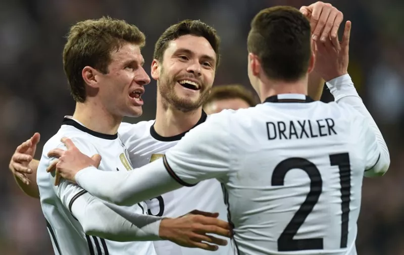 Germany's defender Jonas Hector celebrates scoring the 3-0, his first goal for Germany with Germany's midfielder Thomas Mueller (L) and Germany's midfielder Julian Draxler (R) during the friendly football match Germany vs Italy in Muinch, southern Germany, on March 29, 2016.  / AFP / CHRISTOF STACHE