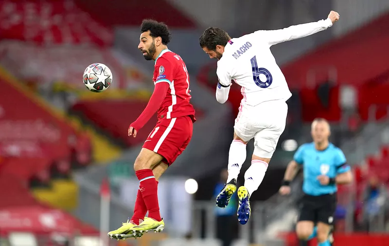 Liverpool's Mohamed Salah, left, jumps for the ball with Real Madrid's Nacho during a Champions League quarter final second leg soccer match between Liverpool and Real Madrid at Anfield stadium in Liverpool, England, Wednesday, April 14, 2021. (AP Photo/Jon Super)