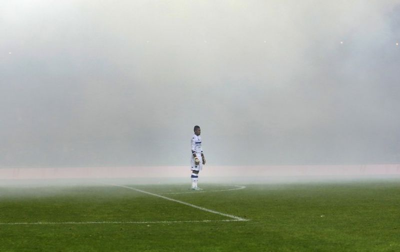 Bastia's French Goalkeeper Alphonse Areola stands in the middle of the smoke caused by fireworks set off by fans during the French L1 football match Saint-Etienne (ASSE) vs Bastia (SCB) at Geoffroy-Guichard stadium in Saint-Etienne, eastern central France, on December 6, 2014. AFP PHOTO / PHILIPPE MERLE / AFP / PHILIPPE MERLE