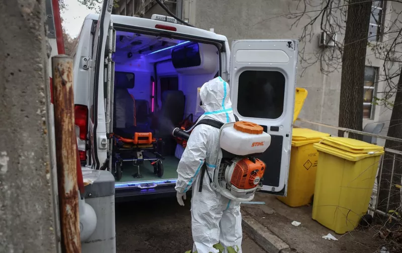 A medical worker disinfects an ambulance outside the Clinic for Infectious and Tropical Diseases in Belgrade on November 24, 2020, as the number of coronavirus (Covid-19) cases rise again in Serbia. - Serbia registered on November 24, 2020, a total of 123,029 cases of the coronavirus infections (6,842 more than the day before) and a total of 1,274 (37 more in a day) people died. (Photo by OLIVER BUNIC / AFP)