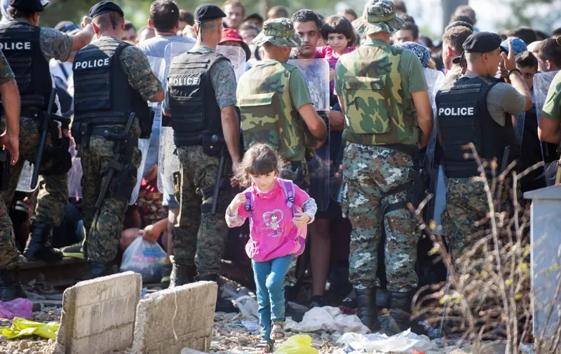 A child walks as migrants wait Macedonian police to allow them to cross in Macedonia at the border line between Greece and Macedonia near the town of Gevgelija on August 25, 2015. More than 1,500 mostly Syrian refugees, trapped in a no-man's land for three days, entered Macedonia from Greece, after police allowed them to pass despite earlier trying to hold back the crowd using stun grenades. Migrants who crossed the Macedonia-Greece border are now streaming into European Union member state Hungary, with a record 2,093 crossing over from Serbia on August 24, 2015. AFP  PHOTO / ROBERT ATANASOVSKI