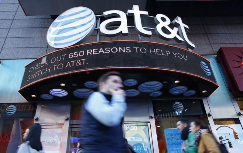 People walk past an AT&amp;T store in New York on October 23, 2016. 
AT&amp;T unveiled a mega-deal for Time Warner that would transform the telecom giant into a media-entertainment powerhouse positioned for a sector facing major technology changes. The stock-and-cash deal is valued at $108.7 billion including debt, and gives a value of $84.5 billion to Time Warner -- a major name in the sector that includes the Warner Bros. studios in Hollywood and an array of TV assets such as HBO and CNN. / AFP PHOTO / KENA BETANCUR