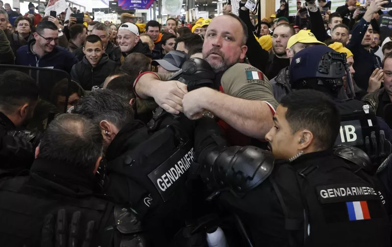 French farmers and gendarmes (bottom) scuffle during a farmers' protest at the Porte Versailles exhibition centre, prior to the opening of the 60th International Agriculture Fair (Salon de l'Agriculture), in Paris, on February 24, 2024. Farmers across Europe have been protesting for weeks over what they say are excessively restrictive environmental rules, competition from cheap imports from outside the European Union and low incomes. (Photo by Kiran Ridley / AFP)