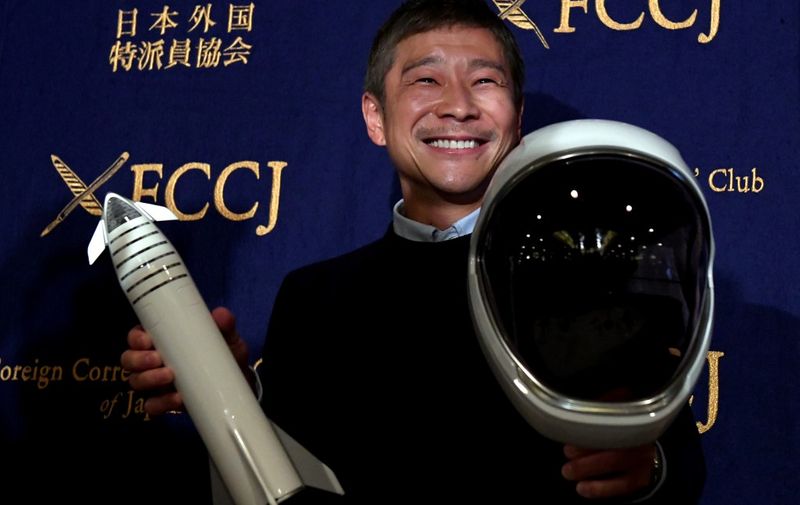 Yusaku Maezawa, entrepreneur and CEO of ZOZOTOWN and SpaceX BFR's first private passenger, poses with a miniature rocket and space helmet prior to start of a press conference at the Foreign Correspondents' Club of Japan in Tokyo on October 9, 2018. - It was confirmed in September that Maezawa will be the first man to fly around the moon on a SpaceX rocket as early as 2023. (Photo by Toshifumi KITAMURA / AFP)