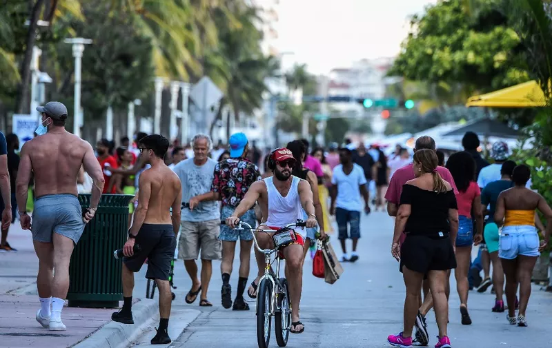 (FILES) In this file photo a man rides a bicycle as people walk on Ocean Drive in Miami Beach, Florida on June 26, 2020. - Florida has registered more than 15,000 new cases of coronavirus in a day, easily breaking a record for a US state previously held by California, according to official numbers published on July 12, 2020.The total of 15,299 cases in the hard-hit southeastern state was up sharply, 47 percent above the previous day's total, the Florida state health department reported. (Photo by CHANDAN KHANNA / AFP)