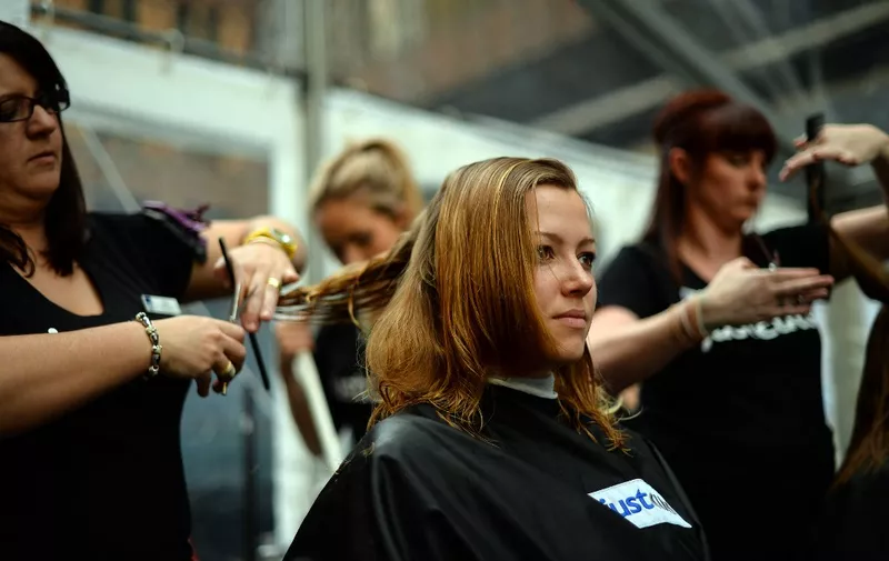 A professional hairdresser gives a free hair cut to a woman in Sydney on August 6, 2013. The Wesley Haircut for homelessness was held at Sydneys Martin Place aimed to break the official world record for the number of haircuts by a team of people in just eight hours. The event was aimed to promote the profile of the issue of homelessness and raise much needed funds for homeless people during Homeless Persons Week .       AFP PHOTO / Saeed Khan (Photo by SAEED KHAN / AFP)