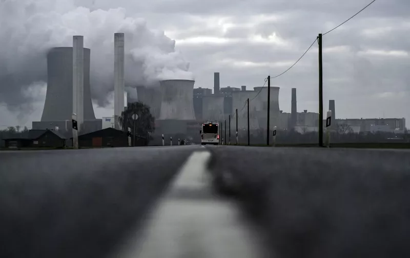(FILES) In this file photo taken on January 17, 2022 a bus drives on a road as steam rises from the cooling towers of the lignite-fired power plant of German energy giant RWE in Niederaussem, western Germany. - Germany said on June 20, 2022 it still aimed to close its coal power plants by 2030, despite a recent decision to revert to the fuel in the midst of an energy crisis provoked by Russia's invasion of Ukraine. "The 2030 coal exit date is not in doubt at all. It is more important than ever that it is realised in 2030," economy ministry spokesman Stephan Gabriel Haufe said at a regular press conference. (Photo by Ina FASSBENDER / AFP)