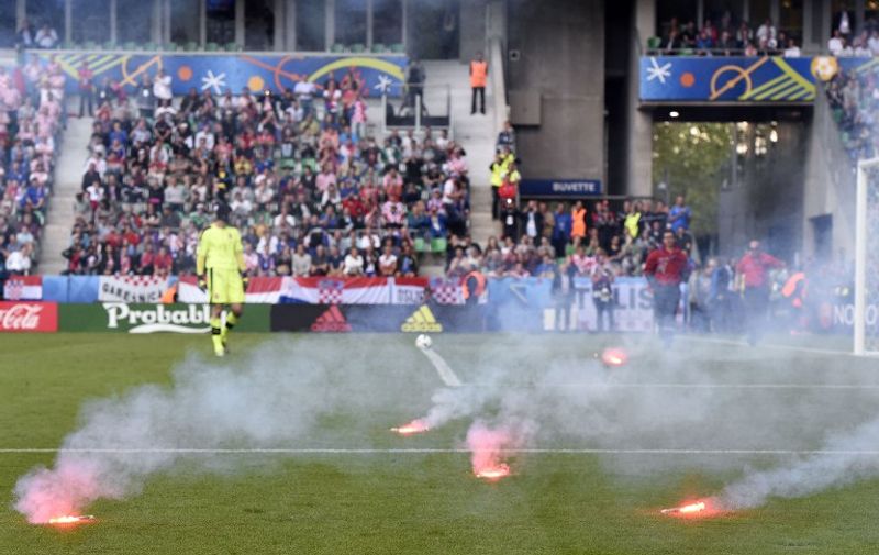 Flares are lobed onto the pitch during the Euro 2016 group D football match between Czech Republic and Croatia at the Geoffroy-Guichard stadium in Saint-Etienne on June 17, 2016. / AFP PHOTO / Joe KLAMAR