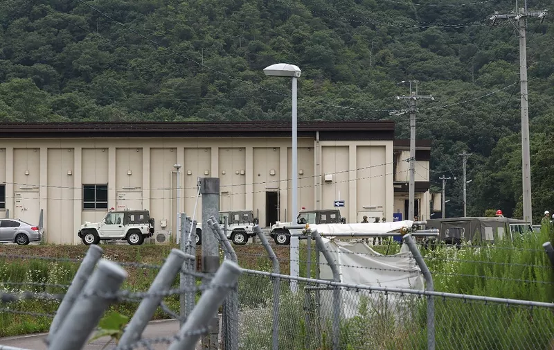 Vehicles and members of Japan's Ground Self-Defense Force (SDF) are pictured outside a building at the Hino basic firing range in the city of Gifu, Gifu prefecture, on June 14, 2023, where a shooting incident occurred at the training range. Two soldiers were killed and a third wounded when a fellow recruit opened fire at the training range in central Japan on June 14, the military said. (Photo by JIJI Press / AFP) / Japan OUT