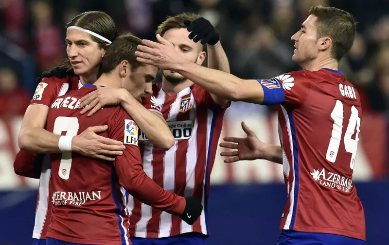 Atletico Madrid's French forward Antoine Griezmann (C) is congratulated by Atletico Madrid's Brazilian defender Filipe Luis (L) and Atletico Madrid's midfielder Gabi (R) after scoring a penalty during the Spanish league football match Club Atletico de Madrid vs Real Sociedad de Futbol at the Vicente Calderon stadium in Madrid on March 1, 2016. / AFP / GERARD JULIEN