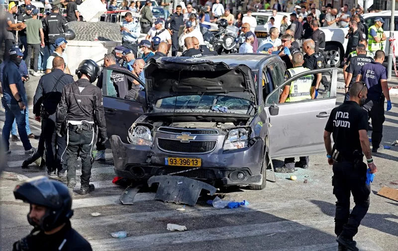 Israeli police and emergency personnel inspect a damaged vehicle following an incident in Jerusalem's Mahane Yehuda market on April 24, 2023. (Photo by AHMAD GHARABLI / AFP)