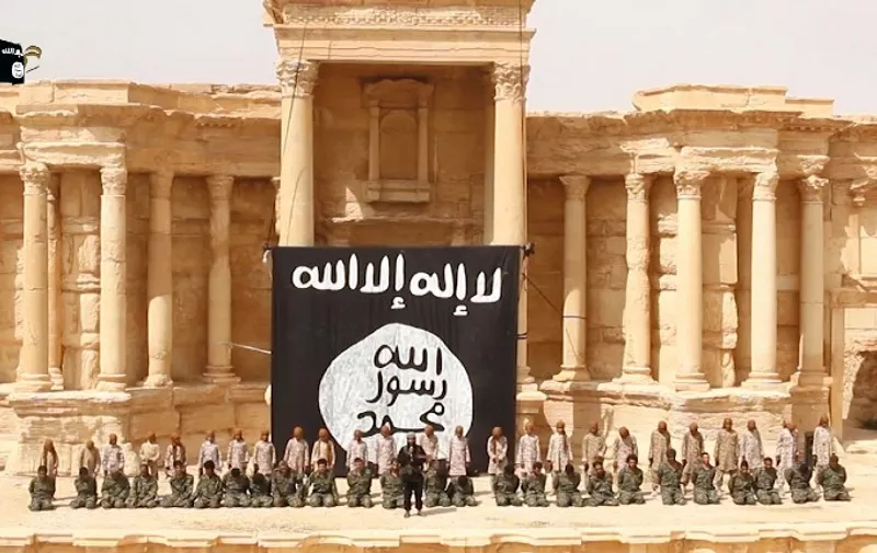 An image grab taken from a video made available by Jihadist media outlet Welayat Homs on July 4, 2015 allegedly shows 25 Syrian government soldiers kneeling in front of, what appears to be children or teenagers wearing desert camouflage, in the ancient amphitheatre in the city of Palmyra, ahead of being executed. The executions in the Palmyra amphitheatre were first reported on May 27 by the Syrian Observatory for Human Rights, a Britain-based monitor, less than a week after IS captured the city. AFP PHOTO / HO / WELAYAT HOMS
=== RESTRICTED TO EDITORIAL USE - MANDATORY CREDIT "AFP PHOTO / HO / WELAYAT HOMS" - NO MARKETING NO ADVERTISING CAMPAIGNS - DISTRIBUTED AS A SERVICE TO CLIENTS FROM ALTERNATIVE SOURCES, AFP IS NOT RESPONSIBLE FOR ANY DIGITAL ALTERATIONS TO THE PICTURE'S EDITORIAL CONTENT, DATE AND LOCATION WHICH CANNOT BE INDEPENDENTLY VERIFIED ===