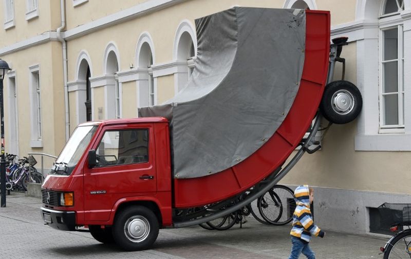 A child walks past the work "Truck" by Austrian artist Erwin Wurm on June 21, 2015 in Karlsruhe, southwestern Germany. The work is part of the exhibition "The City is the Star  Art at the Construction Site" running across the city until September 27, 2015.              AFP PHOTO / DPA / ULI DECK    +++    GERMANY OUY

RESTRICTED TO EDITORIAL USE, MANDATORY MENTION OF THE ARTIST UPON PUBLICATION, TO ILLUSTRATE THE EVENT AS SPECIFIED IN THE CAPTION