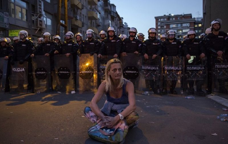 A woman sits in front of a riot police cordon after a standoff during a demonstration against Serbian President Aleksandar Vucic outside the presidential building in Belgrade, on March 17, 2019. - Opposition supporters gathered outside the presidential building during a press conference of Serbian President Aleksandar Vucic, a day after opponents broke into the state-run RTS television building, demanding to address the population, in images aired live. There have been weekly opposition protests since December against what they describe as Vucic's slide towards autocratic rule, while accusing RTS of pandering to the ruling party and demanding more airtime for opposing views. (Photo by Vladimir ZIVOJINOVIC / AFP)