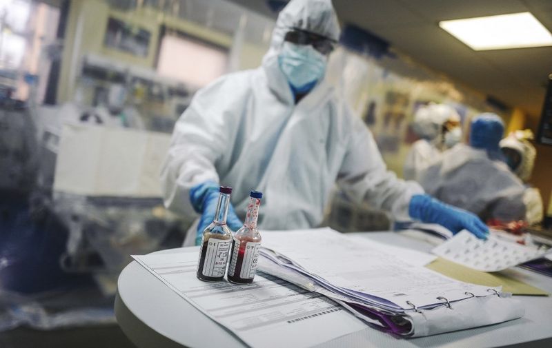 A medical staff member stands past blood samples after taking care of a patient infected with COVID-19 at the intensive care unit of the Franco-Britannique hospital in Levallois-Perret, northern Paris, on April 9, 2020. (Photo by LUCAS BARIOULET / AFP)