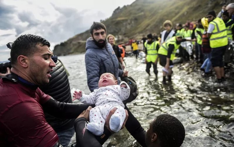Migrant families - helped by rescuers - disembark on the Greek island of Lesbos after crossing with other migrants and refugees the Aegean Sea from Turkey, on November 25, 2015.  More than 800.000 migrants, mostly fleeing war and persecution in Syria, Iraq and Afghanistan, have crossed the Mediterranean this year to reach Europe. AFP PHOTO / BULENT KILIC / AFP PHOTO / BULENT KILIC