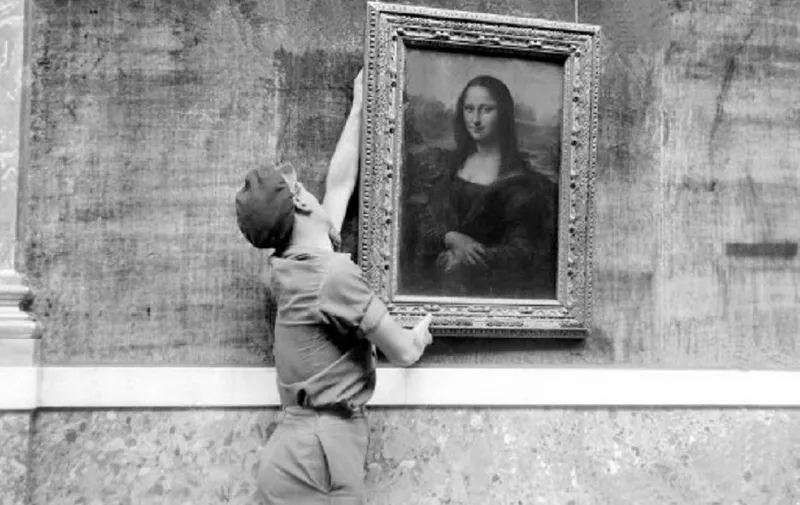 Un employé du musée accroche le célèbre portrait de Mona Lisa plus connu sous le nom de "La Joconde", peinture de Léonard de Vinci (1452-1519), le 6 octobre 1947, lors  de la réouverture de la grande galerie du musée du Louvre. (Photo by - / AFP)