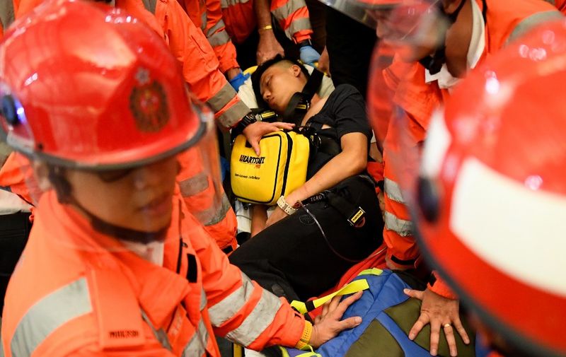 An injured man who was suspected by protestors of being an undercover police officer, is taken away by paramedics at Hong Kongs international airport, late on August 13, 2019. - Hundreds of flights were cancelled or suspended at Hong Kong's airport on August 13, 2019 as pro-democracy protesters staged a second disruptive sit-in at the sprawling complex, defying warnings from the city's leader who said they were heading down a "path of no return". The new protest came as Beijing sent further ominous signals that the 10 weeks of unrest must end, with state-run media showing videos of security forces gathering across the border. (Photo by Manan VATSYAYANA / AFP)