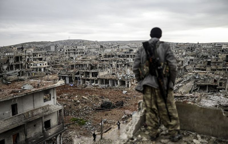 -- AFP PICTURES OF THE YEAR 2015 --
Musa, a 25-year-old Kurdish marksman, stands atop a building as he looks at the destroyed Syrian town of Kobane, also known as Ain al-Arab, on January 30, 2015. Kurdish forces recaptured the town on the Turkish frontier on January 26, in a symbolic blow to the jihadists who have seized large swathes of territory in their onslaught across Syria and Iraq.     AFP PHOTO/BULENT KILIC / AFP / BULENT KILIC