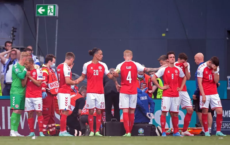 Denmark's players gather as paramedics attend to midfielder Christian Eriksen (not seen) during the UEFA EURO 2020 Group B football match between Denmark and Finland at the Parken Stadium in Copenhagen on June 12, 2021. (Photo by HANNAH MCKAY / POOL / AFP)