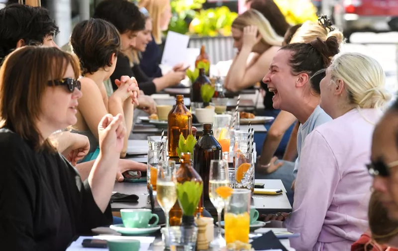 People enjoy a meal at a cafe in Melbourne on October 22, 2021, following the midnight lifting of coronavirus restrictions in one of the world's most locked-down cities. (Photo by William WEST / AFP)