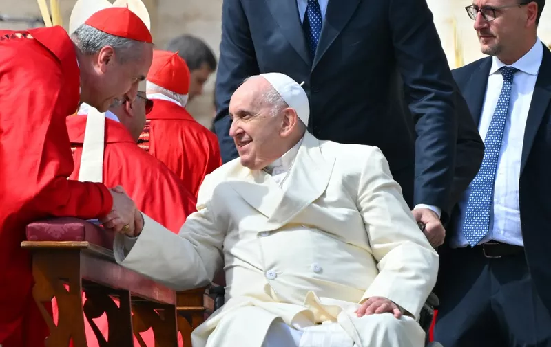 Pope Francis, seated in his wheelchair, goes to salute Cardinals and Bishops at the end of the Palm Sunday mass on April 2, 2023 at St. Peter's square in The Vatican. (Photo by Filippo MONTEFORTE / AFP)