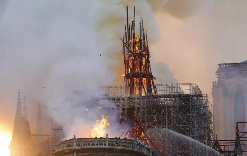 Smoke and flames rise during a fire at the landmark Notre-Dame Cathedral in central Paris on April 15, 2019, potentially involving renovation works being carried out at the site, the fire service said. - A major fire broke out at the landmark Notre-Dame Cathedral in central Paris sending flames and huge clouds of grey smoke billowing into the sky, the fire service said. The flames and smoke plumed from the spire and roof of the gothic cathedral, visited by millions of people a year, where renovations are currently underway. (Photo by FRANCOIS GUILLOT / AFP)