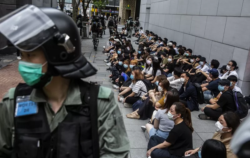 Riot police detain a group of people (R) during a protest in the Causeway Bay district of Hong Kong on May 27, 2020, as the city's legislature debates over a law that bans insulting China's national anthem. - Hong Kong police placed a dragnet around the financial hub's legislature on May 27 and fired pepper-ball rounds in the commercial district as they tried to stamp out protests against a bill banning insults to China's national anthem. (Photo by ISAAC LAWRENCE / AFP)