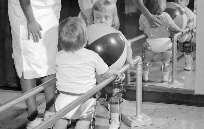 HIL54497CHILDPOLIO

Physical therapist assisting two small children with polio holding on to rail. (Both are in braces).

1963
Charles Farmer, AVS

tray #129, B 54497