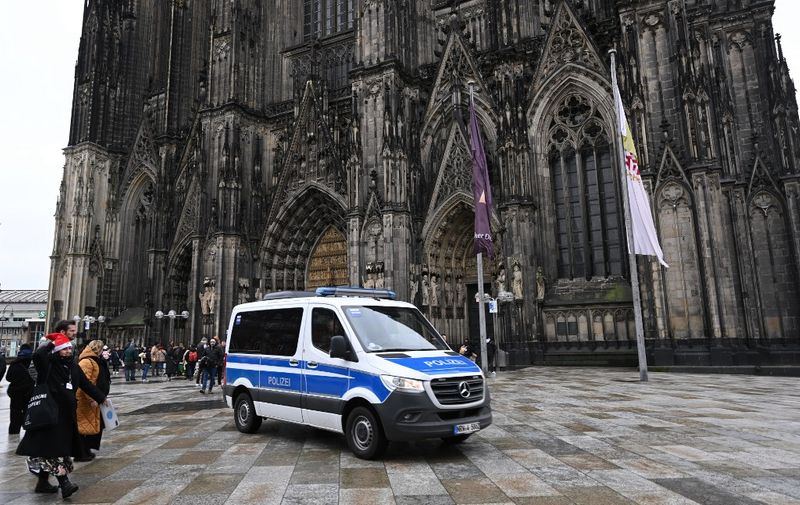 (FILES) A police car drives in front of the Cologne Cathedral on December 24, 2023. German police arrested three people on December 31, 2023 over an alleged attack plot targeting the cathedral in Cologne on New Year's Eve. (Photo by INA FASSBENDER / AFP)