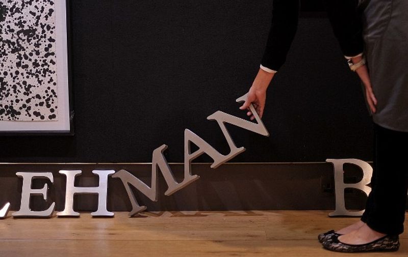 An employee poses for photographers with part of a Lehman Brothers company sign at Christie's auction house in London on September 24, 2010.  The sign will be sold as part of the 'Lehman Brothers: Artwork and Ephemera' sale in London on September 29.     AFP PHOTO / BEN STANSALL / AFP / BEN STANSALL