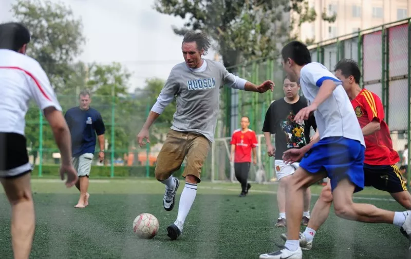 Canadian basketball star Steve Nash (C) plays a pickup game of soccer at the Dongdan courts in central Beijing on August 30, 2009. Nash, a two-time NBA most valuable player with the Phoenix Suns is in Beijing for promotional and charity work, and played a few three-on-three half-court games with local regulars and then crossed over to the soccer pitch to do likewise with the ball kickers. AFP PHOTO/Frederic J. BROWN