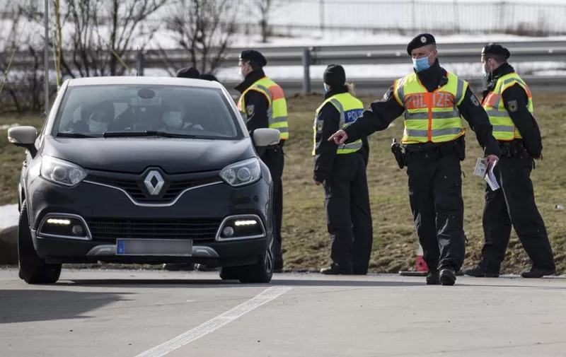 Officers of the Federal Police control a German car at the German-Czech border in an attempt to stem the spread of the new coronavirus variants, in Breitenau, eastern Germany, on February 18, 2021. - Germany partially closed its borders with the Czech Republic and Austria's Tyrol on February 14 over a troubling surge in coronavirus mutations, defying condemnation from the European Union. Germany's new rules on its borders mean only German nationals or residents of Germany are allowed through. Essential workers in sectors such as health and transport can also enter, as well as those crossing for urgent humanitarian reasons, according to the German interior ministry. Everyone must be able to provide a recent negative coronavirus test. (Photo by JENS SCHLUETER / AFP)