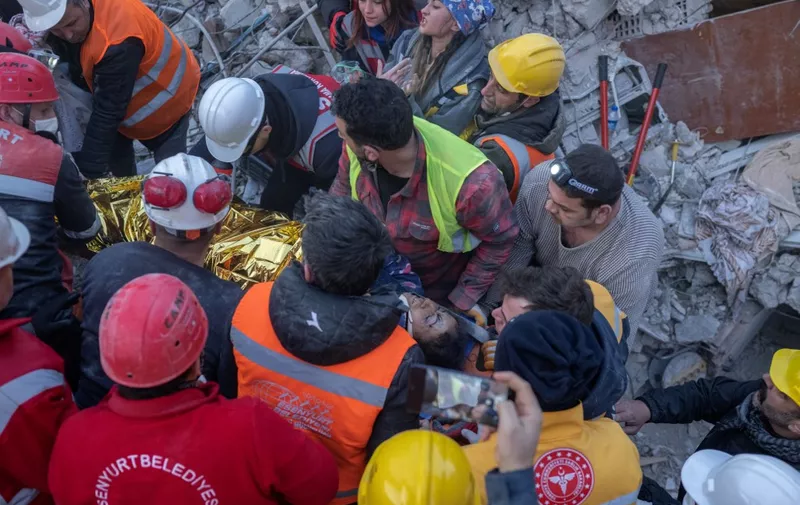 A woman saved by rescue workers is carried to an ambulance, five days following two massive back-to-back earthquakes that struck both Turkey and Syria, in Hatay, southern Turkey on February 10, 2023. - Rescuers pulled out children on February 10, 2023, from the rubble of the Turkey-Syria earthquake that struck on February 6, 2023, as the toll approached 23,000 and a winter freeze compounded the suffering for nearly one million people estimated to be in urgent need of food. (Photo by BULENT KILIC / AFP)