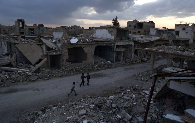 Syrian children walk past heavily damaged buildings in the rebel-held town of Douma, on the eastern edges of the capital Damascus on February 27, 2016, on the first day of the landmark ceasefire agreement. 
Less than a day into a landmark ceasefire deal in parts of the country, residents say their usual routine has been thrown off without the usual sounds of artillery, rocket attacks, or helicopter-borne barrel bombs.

 / AFP / Sameer Al-Doumy