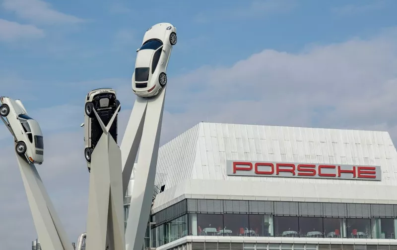 (FILES) This file photo taken on February 21, 2019 shows the sculpture "Inspiration 911", showing three Porsche 911 sportscars from different generations, in front of the headquarters of German luxury car maker Porsche AG in Stuttgart, southwestern Germany. - Prosecutors in Stuttgart said they raided German sports car maker and Volkswagen subsidiary Porsche on Tuesday, May 28, 2019, on suspicion that an auditor was bribed to pass information to the company's tax advisor. (Photo by THOMAS KIENZLE / AFP)