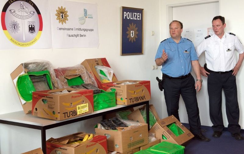 Policemen stand next to black packages and boxes for the transport of bananas that were used for drug smuggling at the State Office of Criminal Investigation in Berlin on May 4, 2015. More than 380 kilos of cocaine turned up on May 4, 2015, in boxes of bananas delivered to Aldi supermarkets in and around Berlin, police said. Staff working at 14 of the discount supermarkets reported the stashes of narcotics tucked in the produce deliveries from Colombia, which police believe ended up at the stores by accident. AFP PHOTO / DPA / SOEREN STACHE +++ GERMANY OUT