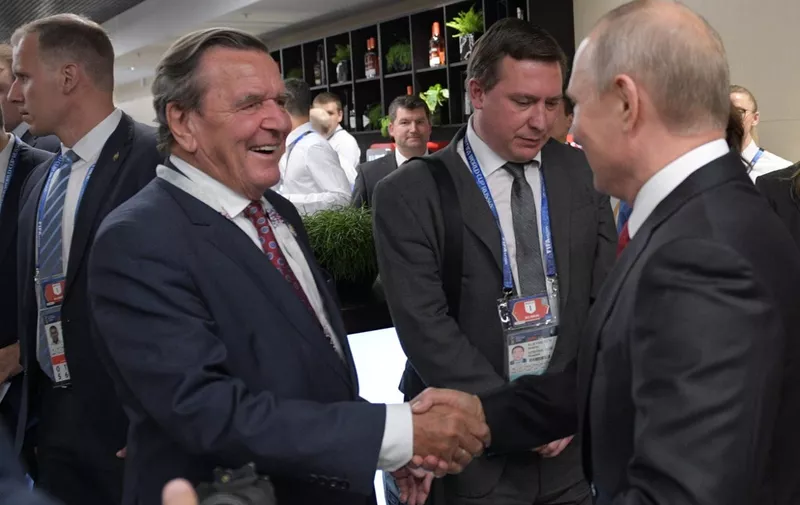 Russian President Vladimir Putin (R) shakes hands with Germany's former chancellor Gerhard Schroeder at the half-time during the Russia 2018 World Cup Group A football match between Russia and Saudi Arabia at the Luzhniki Stadium in Moscow on June 14, 2018. (Photo by Alexey DRUZHININ / SPUTNIK / AFP)