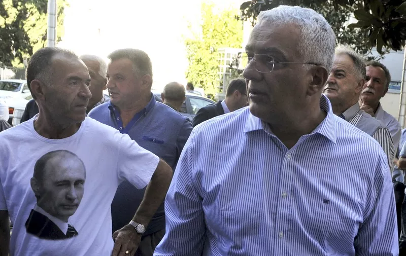 Montenegro's opposition Democratic Front (DF) leaders Andrija Mandic (R) stands next to a supporter wearing a t-shirt with a picture of Russian President Vladimir Putin in front of a court in Podgorica on September 6, 2017. - The trial of 14 suspects accused of plotting to overthrow the Montenegro's government and detain the Balkan country outside NATO was resumed on September 6. (Photo by Savo PRELEVIC / AFP)